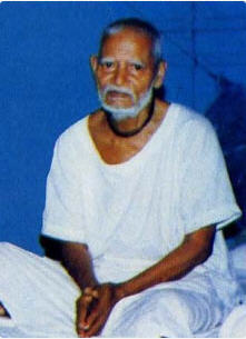 Srila Akincana Krishna Dasa Babaji Maharaja, seated in a simple white cloth