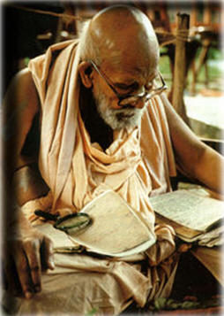 Srila Bhakti Promode Puri Goswami Maharaja seated with manuscripts, magnifying glass and papers, at editorial work in his later years