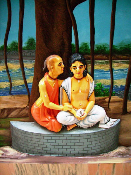 A devotional painting of Isvara Puri seated beneath a tree by a riverbank at Gaya, giving initiation to the young Nimai Pandita