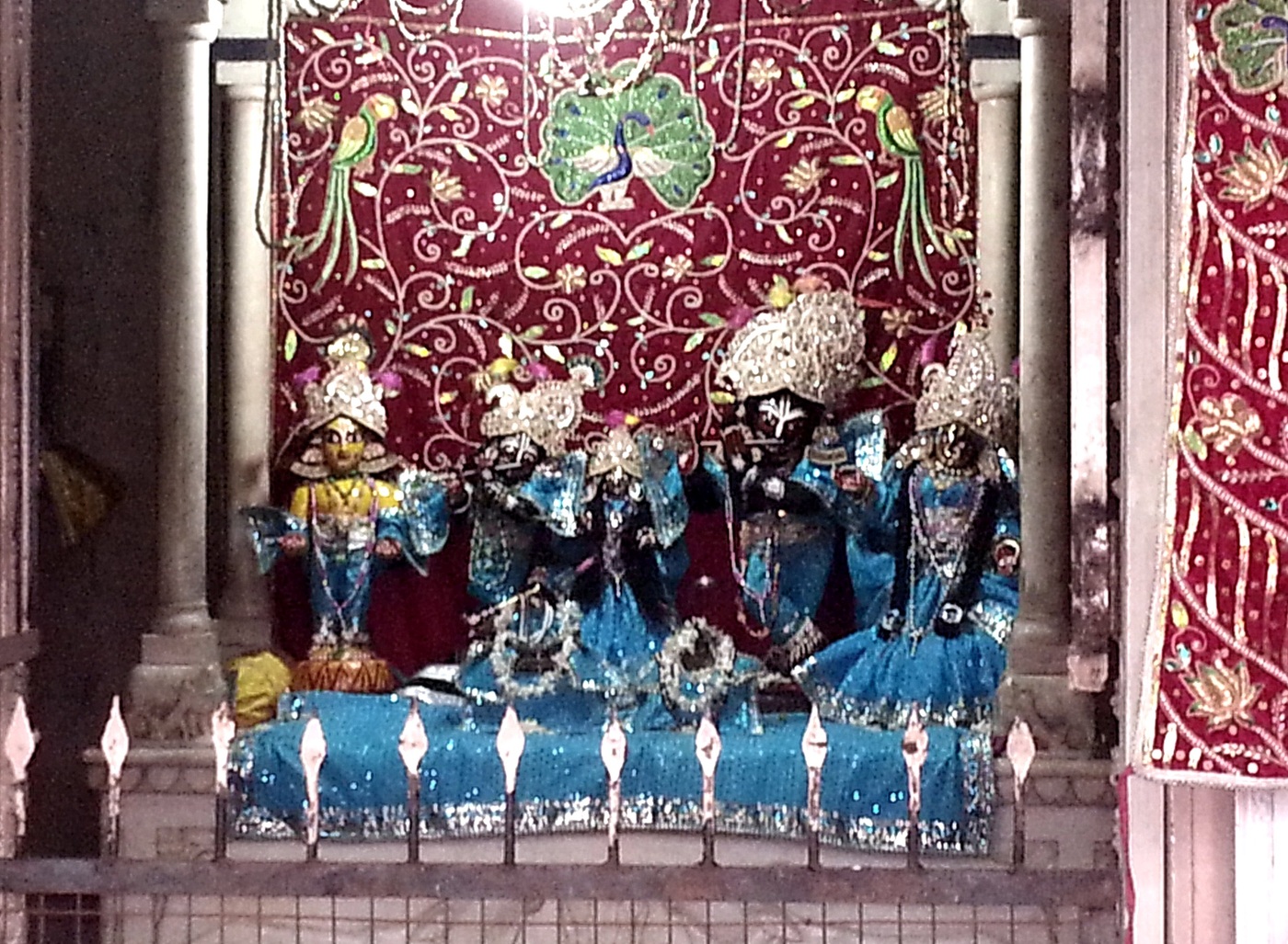 Deities of Radha-Vinoda and attendant figures on a temple altar in Vrindavana.