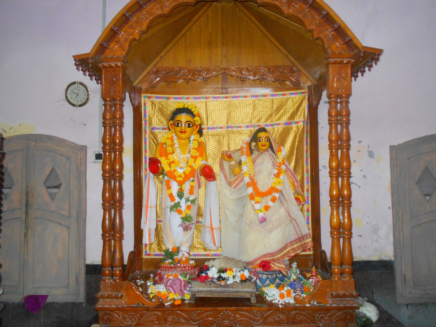 A wider view of the altar at Sitanath Advaita Mandir, Nabadwip, showing the wooden Deities of Advaita Acharya and Sita Devi standing together.